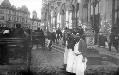 1913年、サンクトペテルブルクのネフスキー大通り、ニコラス駅の外にいるポーターと乗客 作： Russian Photographer